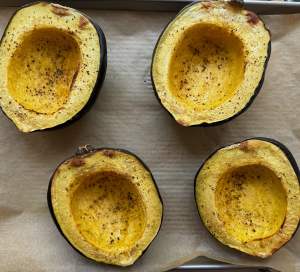 open faced acorn squash on a parchment-lined baking sheet