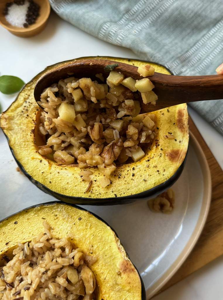 scooping filling into vegan stuffed acorn squash with wild rice