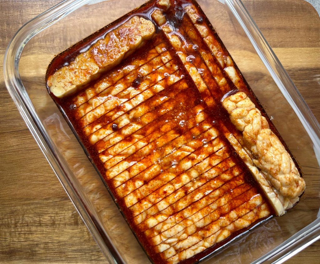 smoky maple tempeh bacon marinating in a glass dish