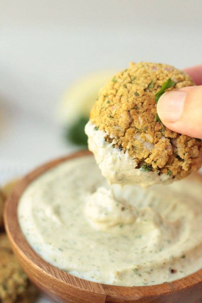 baked falafel being dipped into garlic tahini sauce