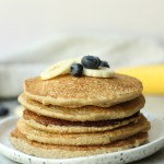 stack of banana oat pancakes with bananas and blueberries on top