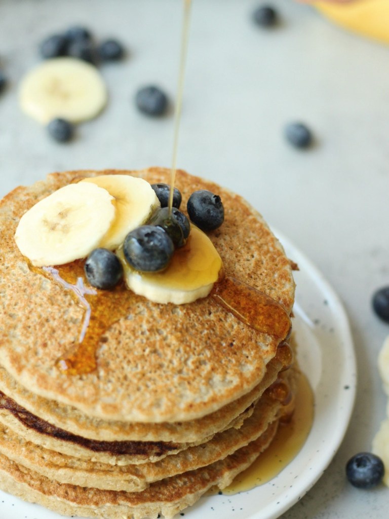 banana oat pancakes with syrup being poured on top