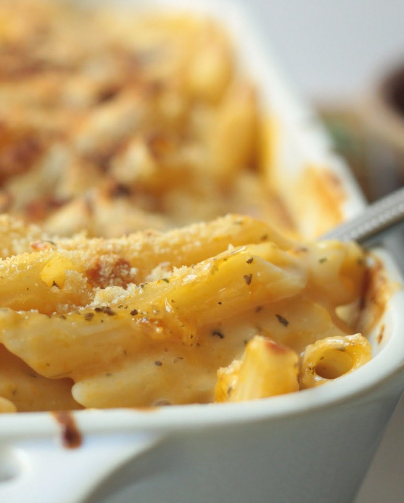 finished vegan butternut squash mac and cheese in the baking dish with scoop being taken out