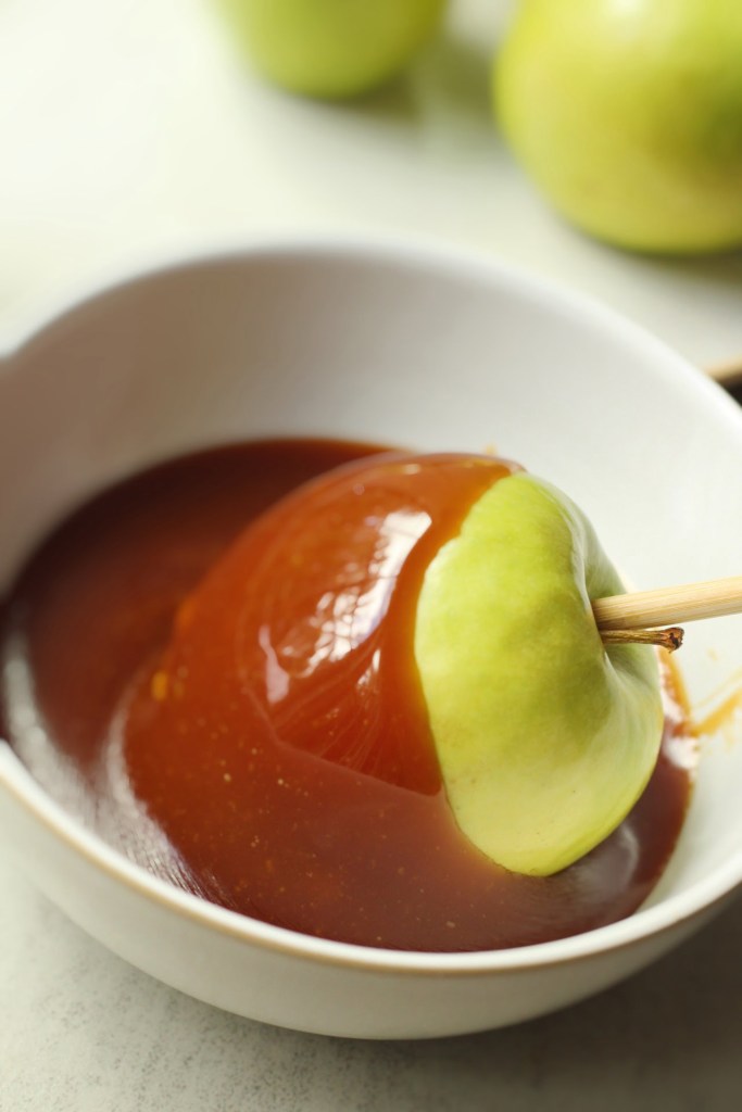 vegan caramel apple being dipped in caramel