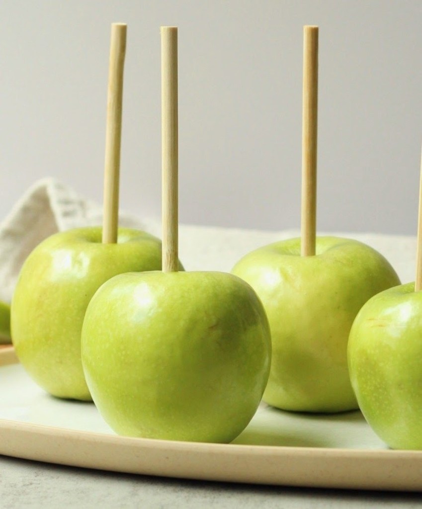 granny smith apples with stick in them in prep for vegan caramel apples