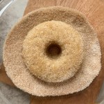 single vegan cinnamon sugar donut being coated in cinnamon sugar