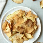 air fryer apple chips on a white plate with a gray background