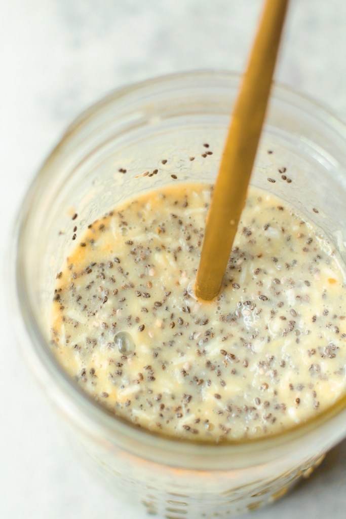 mason jar showing vegan coconut mango chia pudding after being stirred