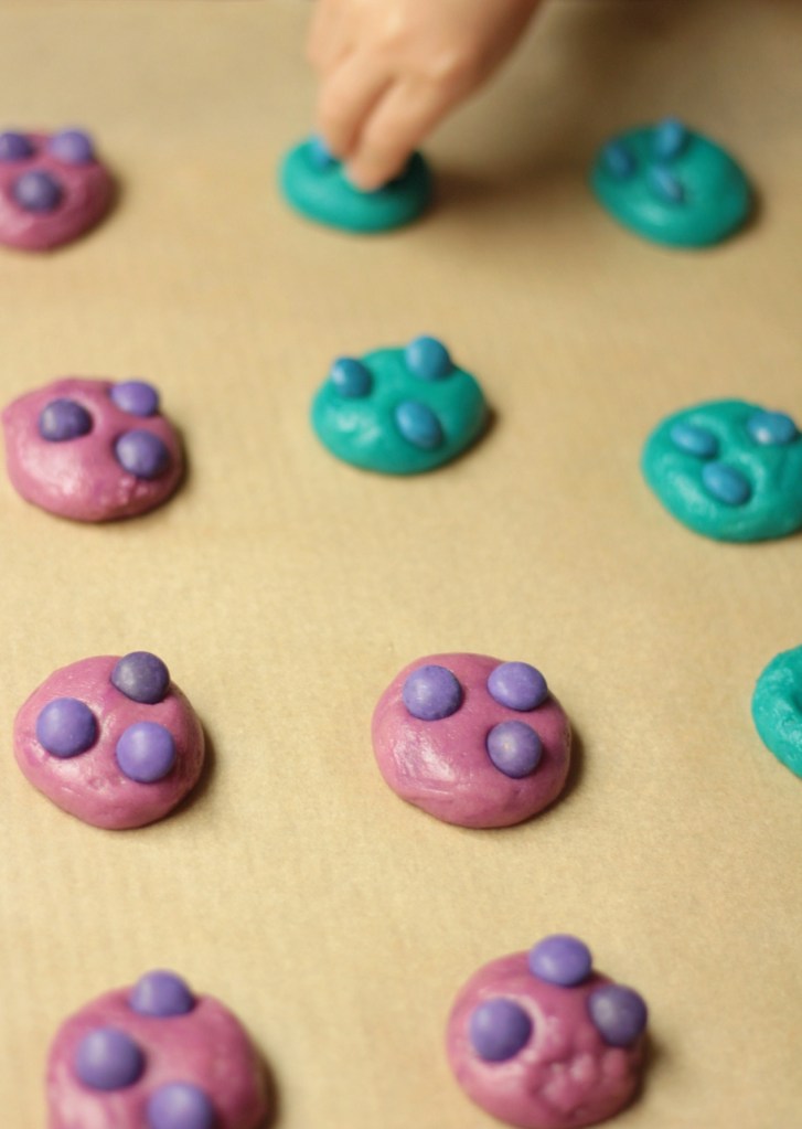 candy pieces being placed into allergy-friendly halloween monster cookies