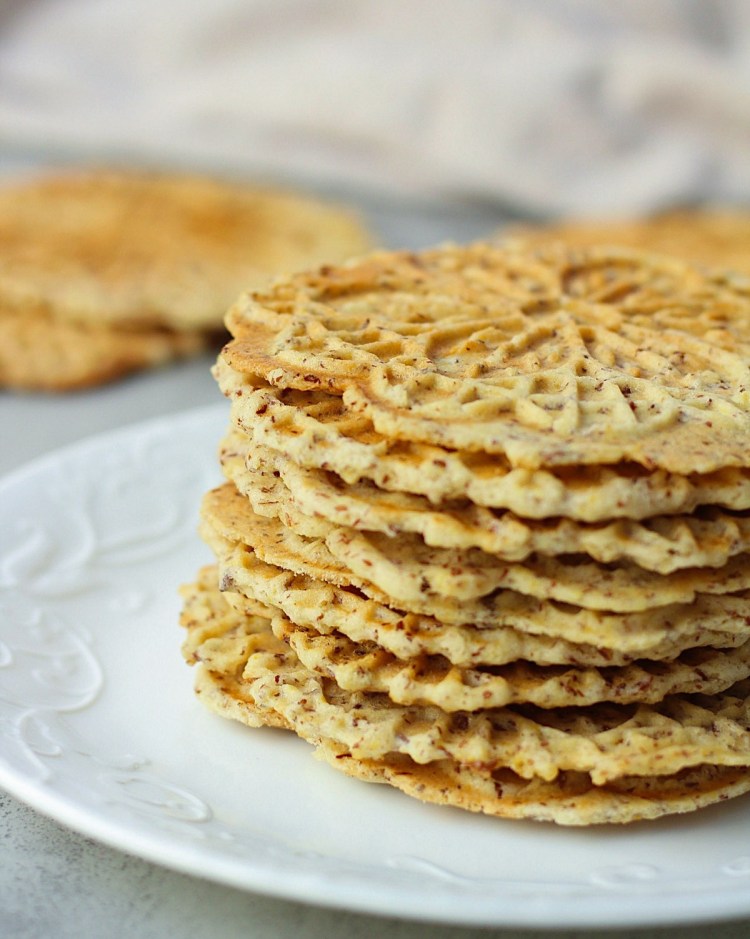 vegan lemon pizzelle stacked on a white plate