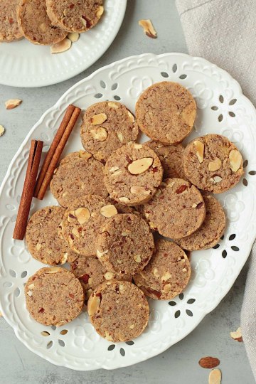 top view of keto almond cookies on white plate with cinnamon sticks