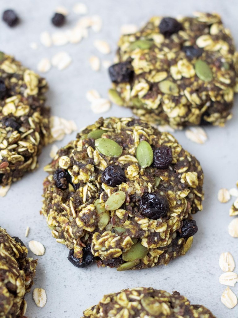 oatmeal protein cookies on a gray surface surrounded by raw oats