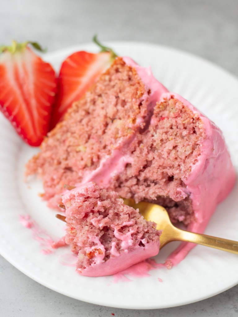 slice of strawberry cake on white plate with forkful taken out