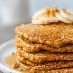 stack of carrot cake pancakes with syrup dripping down side