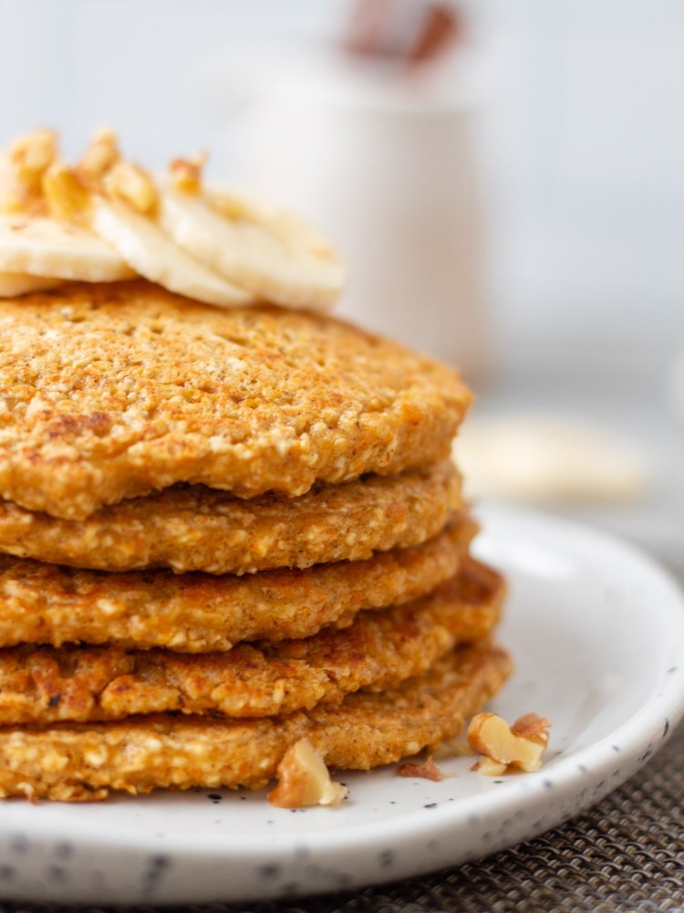 stack of carrot cake pancakes with bananas and walnuts on top