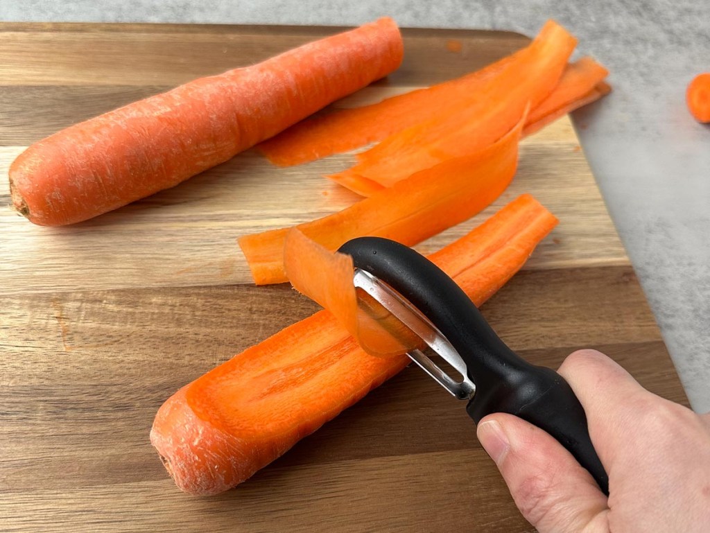 vegetable peeler slicing carrots to make vegan carrot bacon