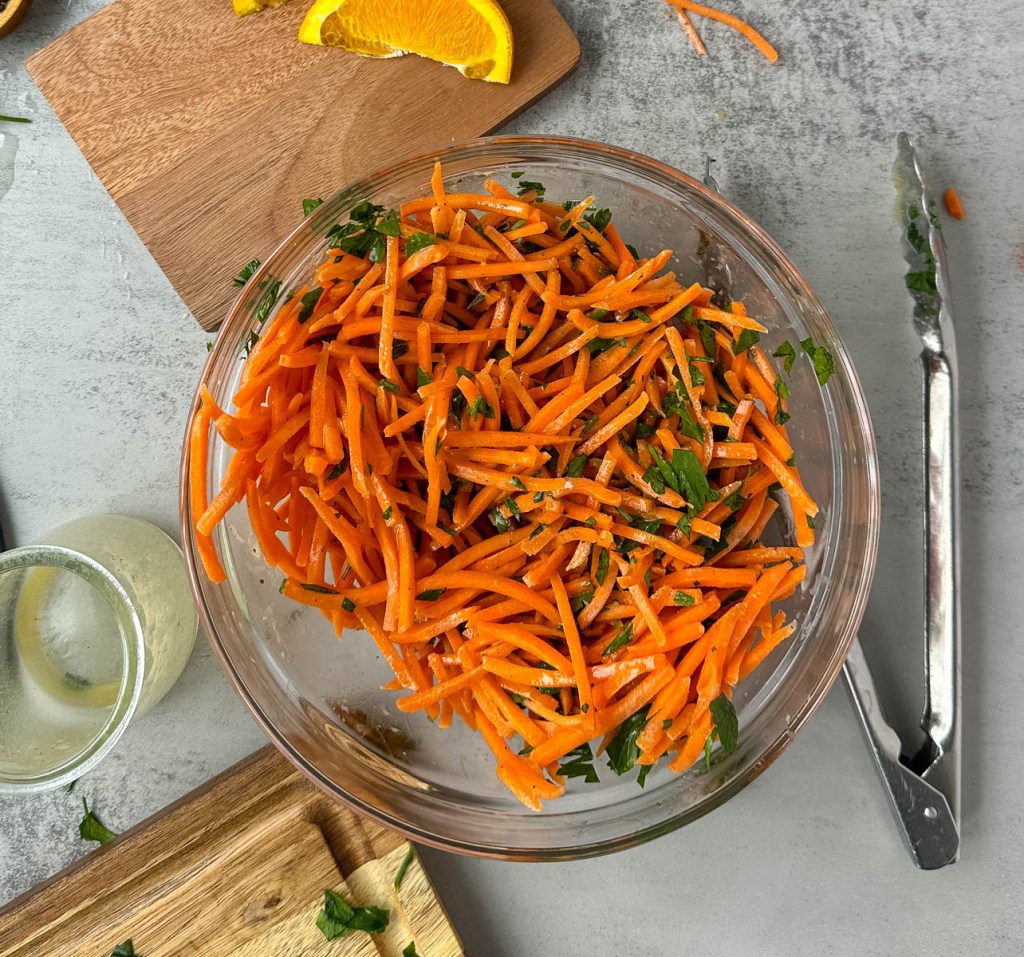 Moroccan Carrot salad being mixed with tongs