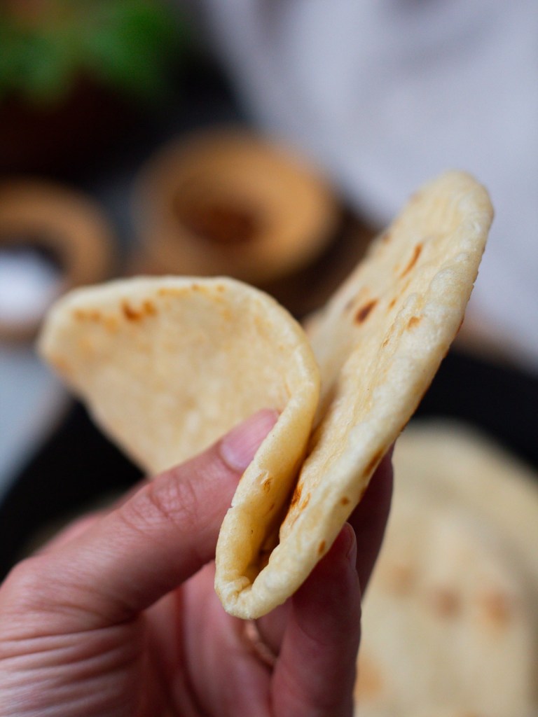 tortilla being folded by a hand to show softness