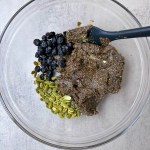 protein bar mixture in a bowl with pumpkin seeds and dried blueberries