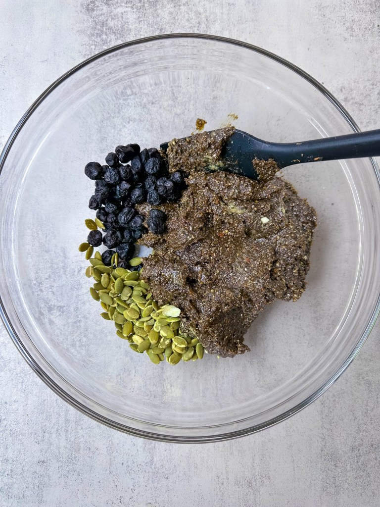 protein bar mixture in a bowl with pumpkin seeds and dried blueberries