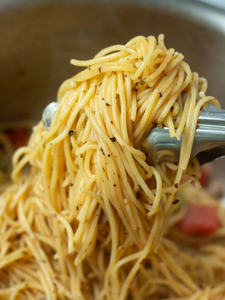 tongs scooping pasta from pot