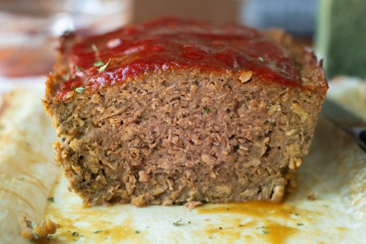Close up view of meatloaf with slice cut off.